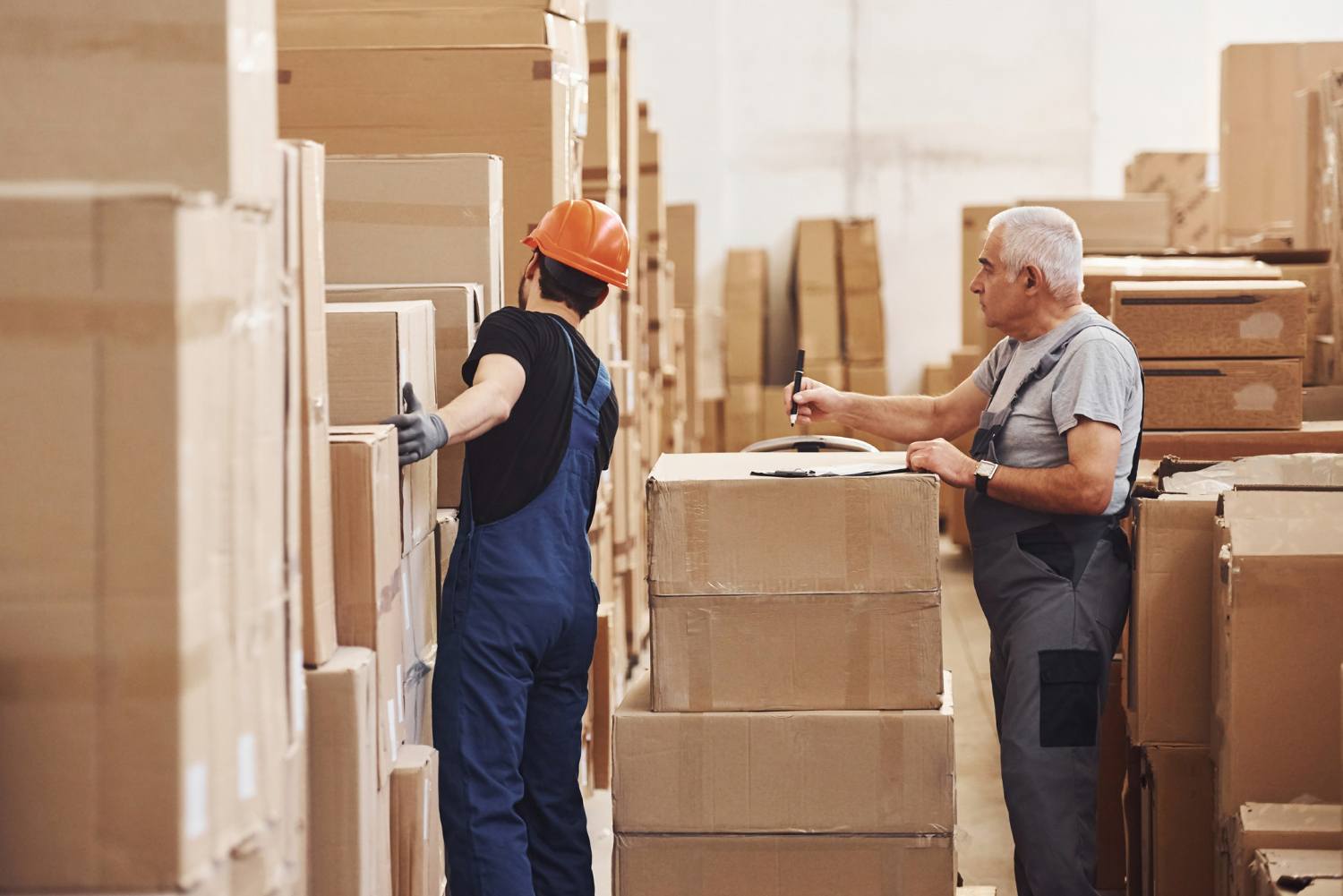 Anbarda qutuları yoxlayan iki Alyans Supply əməkdaşı